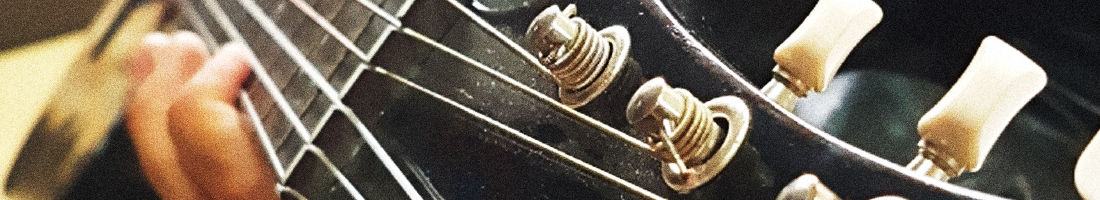 Primer plano de la cabeza de una guitarra acústica y unas manos tocando las cuerdas