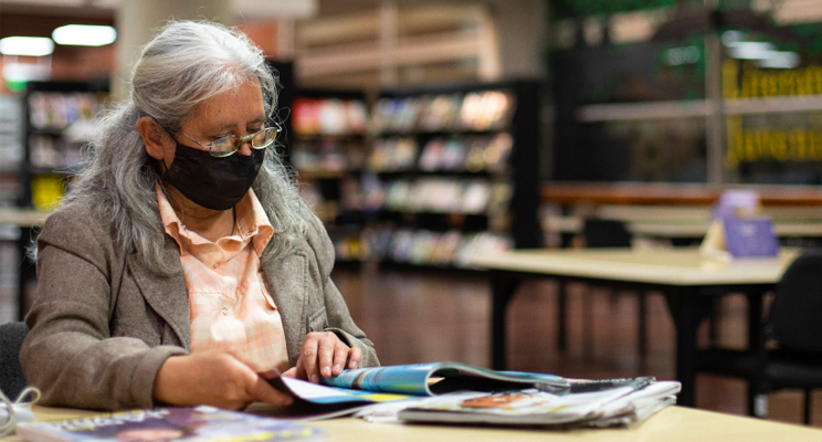 Adulta mayor con tapabocas leyendo en la biblioteca