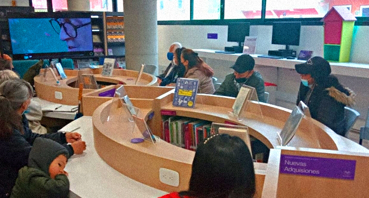 Fotografía de adultos mayores en espacio de taller en la biblioteca prestando atención a una pantalla