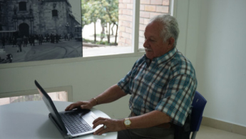 Hombre de la tercera edad, sentado, mirando un computador portátil