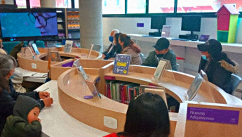 Fotografía de adultos mayores en espacio de taller en la biblioteca prestando atención a una pantalla