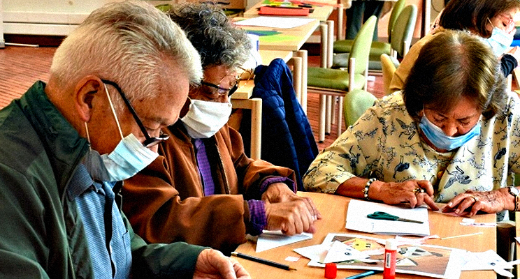Personas de la tercera edad concentradas en un espacio de taller en la biblioteca.