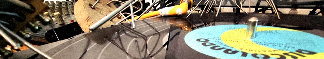 Fotografía de un disco de vinilo junto a un tornamesa y cables al fondo