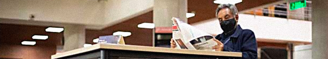 Fotografía de un adulto mayor leyendo un periódico en la bilbioteca