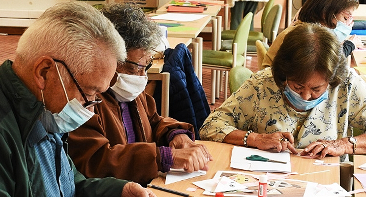 Foto de adultos y adultas mayores trabajando con sus manos sobre una mesa de taller.