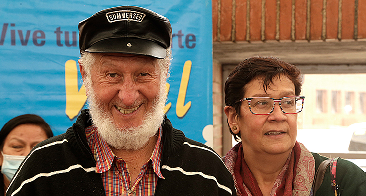 Fotografía de dos adultos mayores, un hombre con barba blanca sonriendo y una mujer con gafas mirando hacia su izquierda