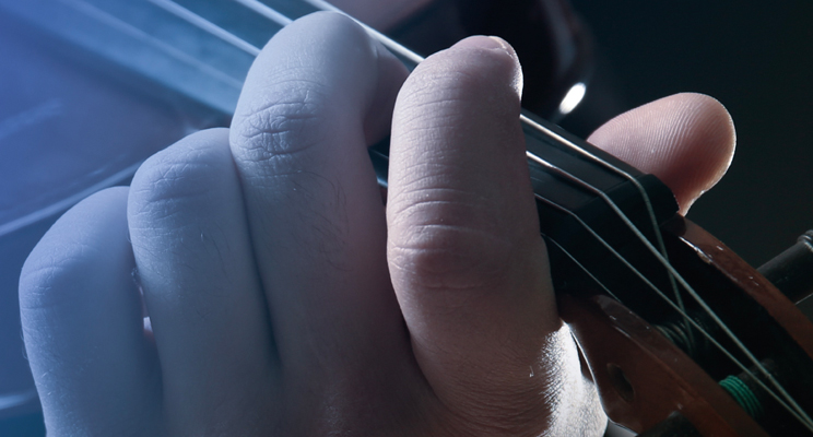 Parte de la pieza promocional donde se ve una foto en primer plano de una mano interpretando el violín.