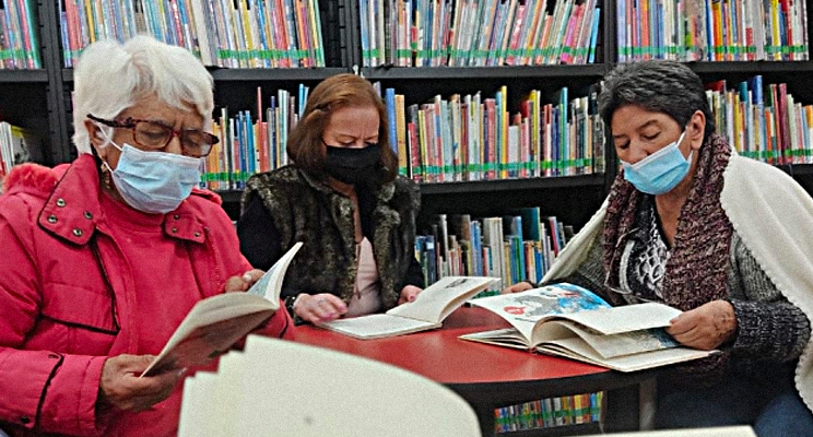Señoras de la tercera edad leyendo concentradas en la biblioteca