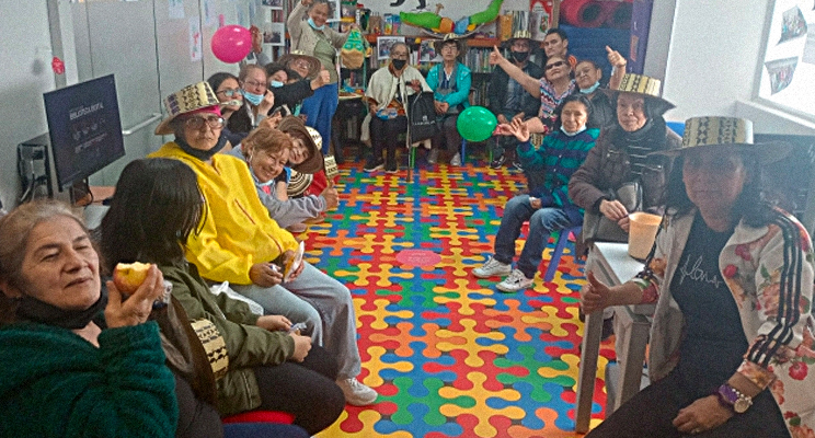 En la foto se puede apreciar un grupo de mujeres adultas mayores compartiendo en un espacio de taller en la biblioteca.