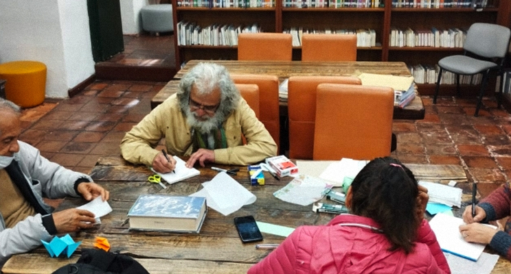 Señores de la tercera edad escribiendo en la biblioteca