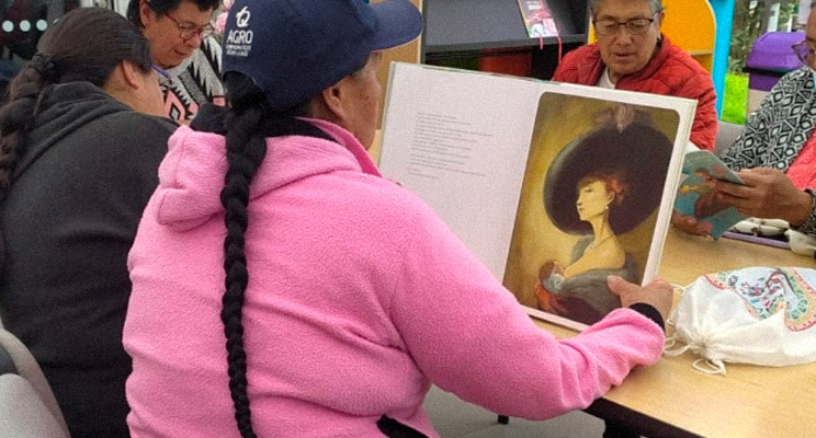 Señoras de la tercera edad leyendo libros de arte concentradas en la biblioteca