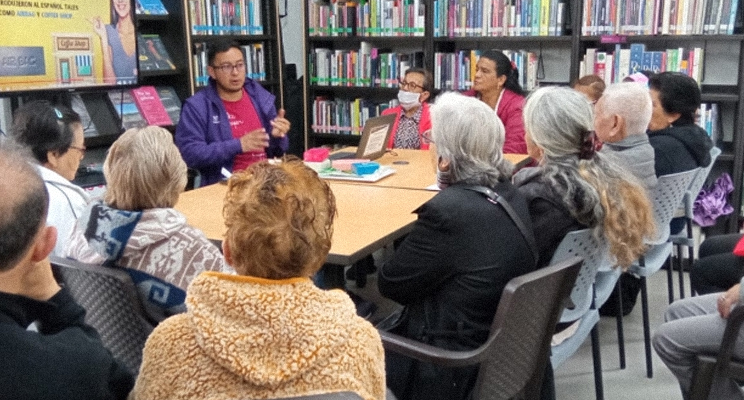 Grupo de adultas mayores compartiendo lectura en la biblioteca