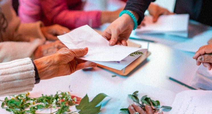 manos de adultos mayores intercambiando cartas en el espacio de taller