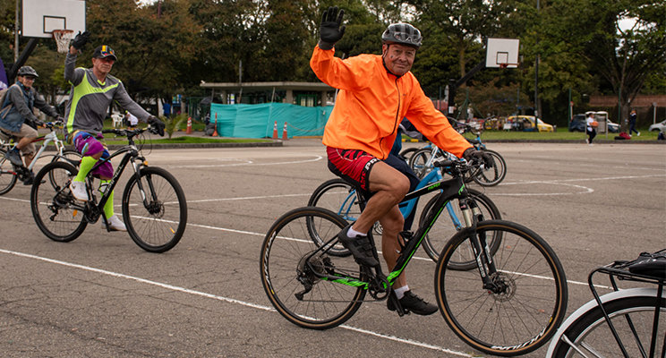 Adultos mayores montando bicicleta sonriendo y saludando