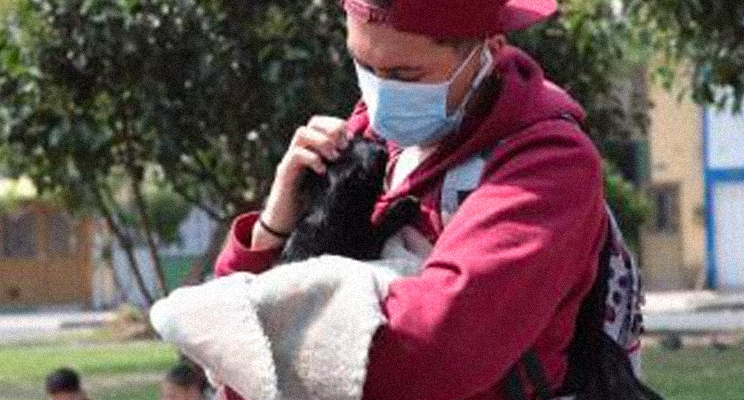 Colaborador del Instituto Distrital de Protección y Bienestar Animal con un perrito en sus manos consintiéndolo