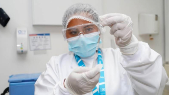 Foto de una colaboradora de la secretaria de salud manipulando los instrumentos necesarios para aplicar una vacuna.