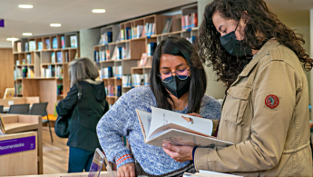 Foto de dos mujeres leyendo en la biblioteca