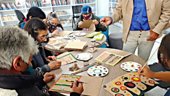 Fotografía de varios adultos(as) mayores en la biblioteca realizando un taller de habilidades manuales