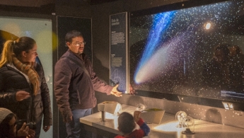 Un mujer y un hombre mirando el universo sobre una pantalla en el Planetario de Bogotá