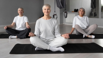 Tres mujeres adultas mayores realizando yoga en un espacio cerrado