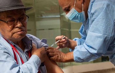 En la foto apreciamos a Don Carlos Julio Chaparro pensionado del FONCEP, al cual le están aplicando una vacuna por parte de Carlos Solórzano, colaborador de la Secretaría Distrital de Salud. - Foto: FONCEP