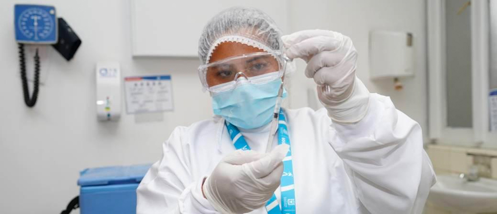 Foto de una colaboradora de la secretaria de salud manipulando los instrumentos necesarios para aplicar una vacuna.