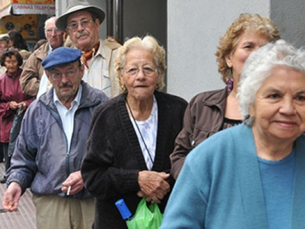 hombres y mujeres de la tercera edad haciendo fila en una calle